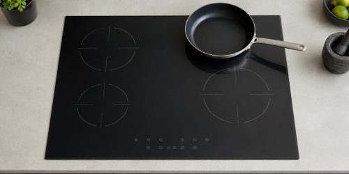 placa-induccion-cocina-sevilla Placa de inducción enrasada en la encimera con mandos táctiles y una sartén apoyada.